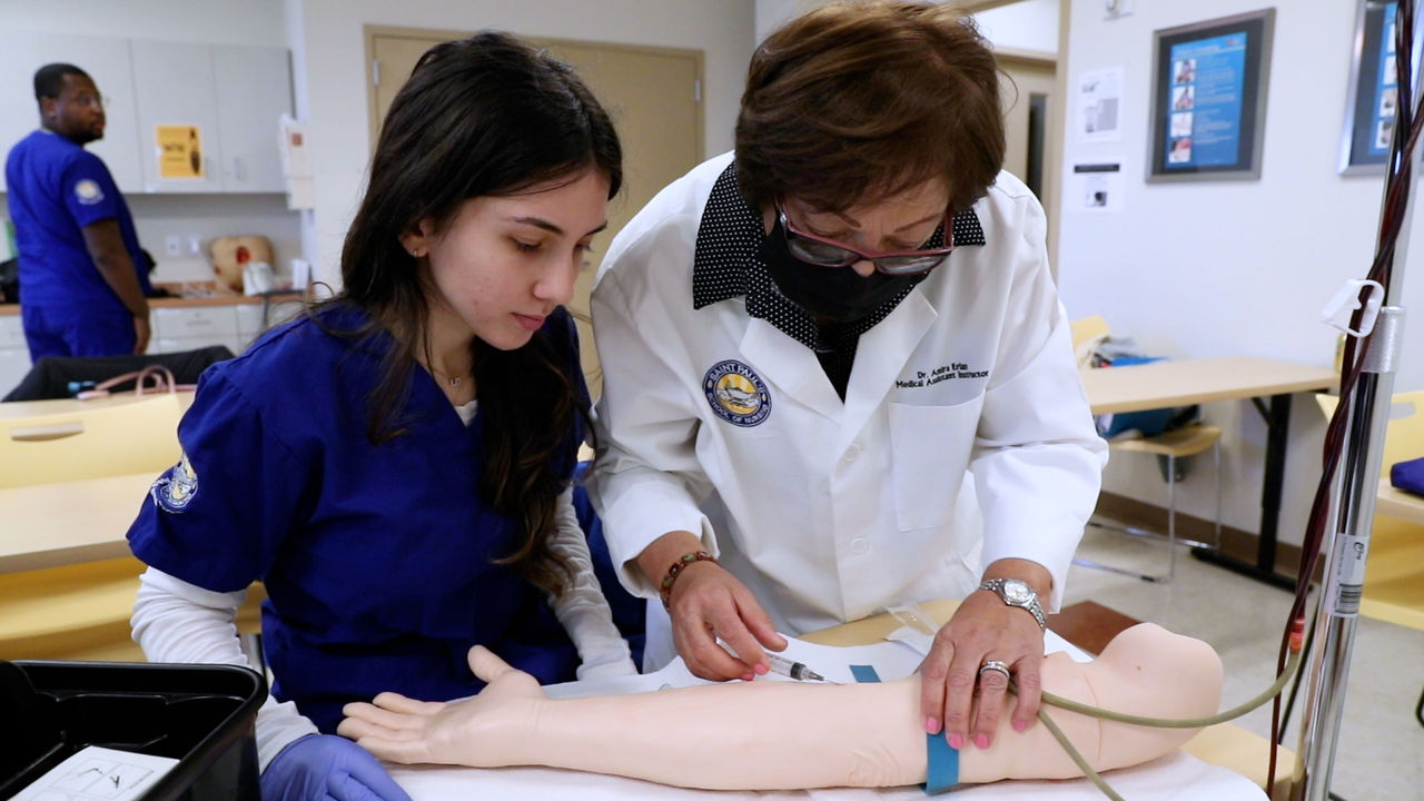 Medical students practice venipuncture on training arm model